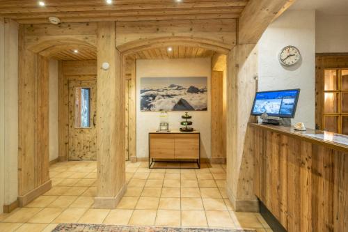 Großes Zimmer mit Holzwänden und einem TV auf der Theke. in der Unterkunft Hotel Sarazena in Zermatt