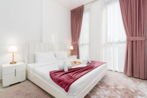 a white bedroom with a large bed with a tray on it at Modern 1-bedroom apartment in family-friendly residence with Swimming Pool, Gym & Free Parking. in Dubai