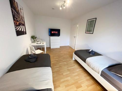 una camera con due letti e una tv di Work & Stay Apartment with Balcony a Osnabrück