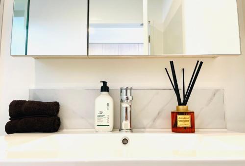 a bathroom sink with two bottles of soap and a mirror at Sunny Oasis- Modern Loft Hidden on Cashel in Christchurch