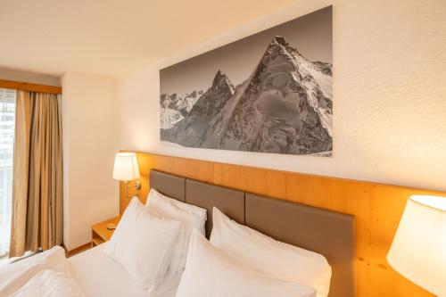 a hotel room with a bed with white pillows at Hotel Sarazena in Zermatt