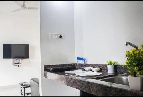 a kitchen counter with a sink and a tv at Hooliv Tamara 103 in Pune