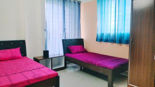 a room with two beds with purple cushions and windows at Hooliv Tamara 103 in Pune