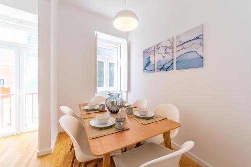 uma sala de jantar com uma mesa de madeira e cadeiras brancas em Amaro II - Sleek 2 bedroom apartment in Alcantara em Lisboa