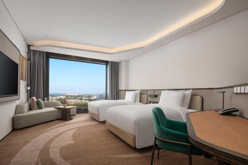 a hotel room with two beds and a large window at Radisson Collection Lingang Shanghai in Shanghai