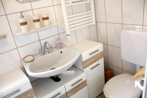 een witte badkamer met een wastafel en een toilet bij NEU! Ferienhaus Weitblick am Großen Meer in Südbrookmerland