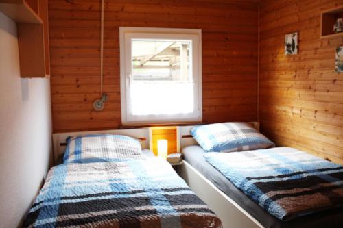 twee bedden in een kleine kamer met een raam bij NEU! Ferienhaus Weitblick am Großen Meer in Südbrookmerland