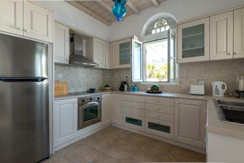 een keuken met witte kasten en een roestvrijstalen koelkast bij La Chapelle Ouest & Guest suite in Agios Romanos