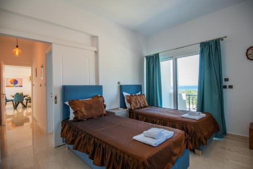 two beds in a room with a window at Istron MiraBella Villas in Istron