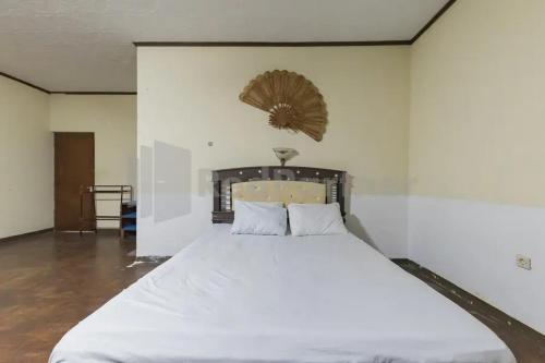 a bedroom with a large bed with white sheets at Hotel Linggarjati near Natural Park TWA Linggarjati in Bojong