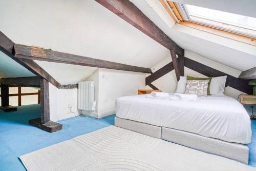 une chambre avec un lit blanc dans un grenier dans l'établissement Studio proche Mairie du 14e arrondissement - II, à Paris