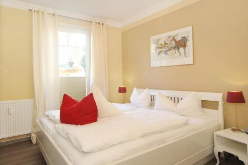 een wit bed met rode kussens in een kamer bij Ferienwohnung Hamburg in Boltenhagen