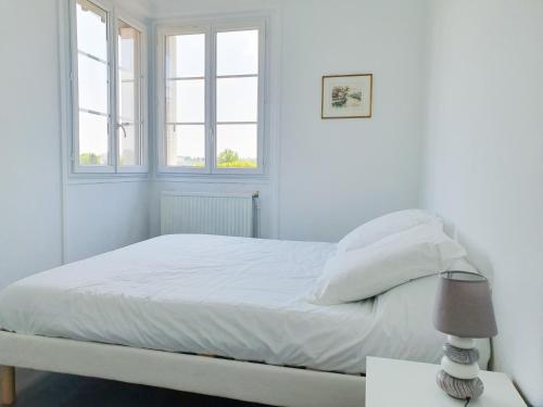 a white bedroom with a bed and two windows at EXIGEHOME-Appart très lumineux aux portes de Paris in Suresnes