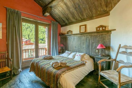 a bedroom with a bed and a chair and a window at Le Chalet à Val d'Isère in Le Joseray