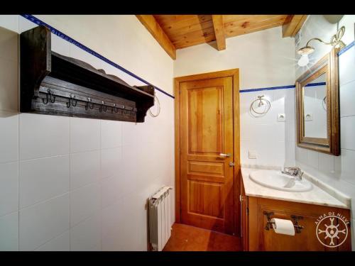 a bathroom with a sink and a wooden door at PASSARELLS de Alma de Nieve in Gessa
