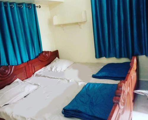 a bedroom with two beds and blue curtains at Nidhivan Residency in Navadwīp