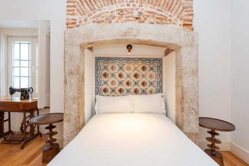 a bed in a room with a brick wall at Casas da Baixa - Jules & Madeleine in Lisbon