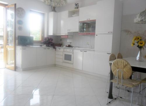 a kitchen with white cabinets and a table and chairs at Casa Le Ancore in Riposto