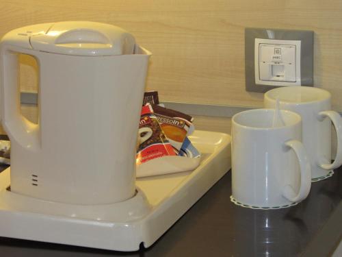 a white tea kettle and two cups on a counter at Holiday Inn Express Valencia Bonaire, an IHG Hotel in Aldaya