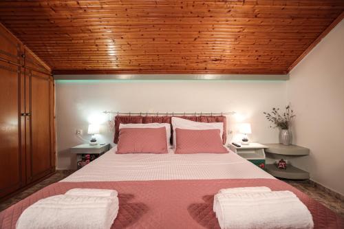 a bedroom with a large bed with two pink pillows at Nona's Central House 3bd in Zakynthos