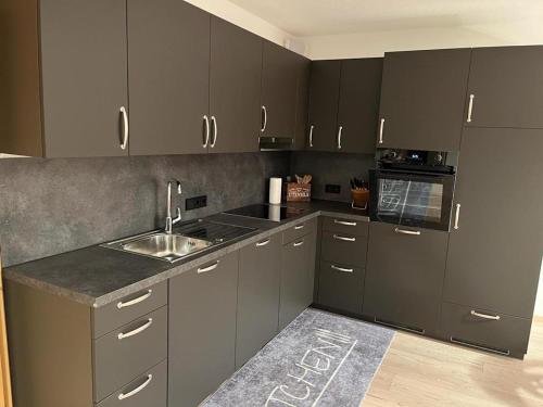 a kitchen with dark gray cabinets and a sink at Berghaus in Ellmau