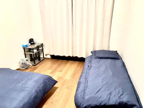 - une chambre avec 2 lits et un rideau dans l'établissement Shinjuku Hana House 4mins to Ōkubo Station, à Tokyo