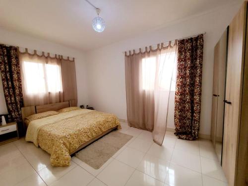 1 dormitorio con 1 cama y 2 ventanas en Maison rénovée à Itaosy Cité Akany Sambatra, en Antananarivo