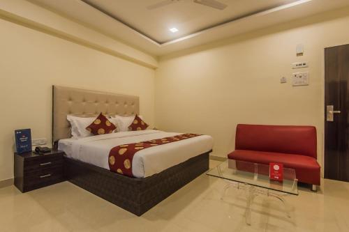um quarto com uma cama e uma cadeira vermelha em Hotel Palace Inn Near Don Bosco -Borivali- Metro Station em Mumbai