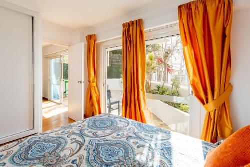 a bedroom with orange curtains and a bed and a balcony at Royal Park Torviscas Beach in Adeje