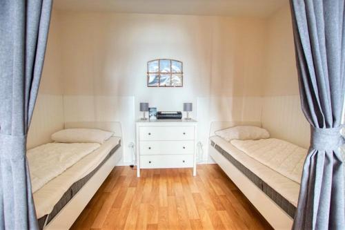 - 2 lits dans une chambre avec des rideaux et une commode dans l'établissement Ferienpark - Haus G, App 0G0305, à Heiligenhafen