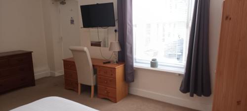 a bedroom with a bed and a desk and a window at Riverdale Hall Hotel & Leisure in Bellingham