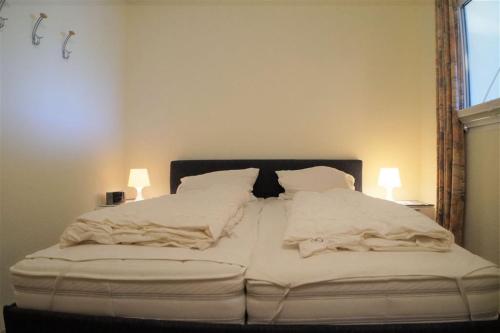 uma cama grande com lençóis brancos e almofadas em Ferienpark - Haus G, App 0G0308 em Heiligenhafen