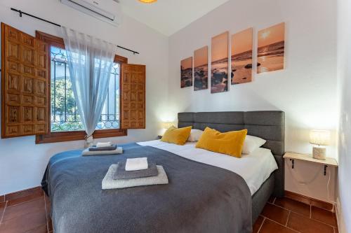 una camera da letto con un letto con cuscini gialli e una finestra di Villa Fenavista a Mijas