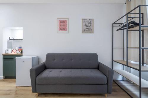 - un canapé gris dans une chambre avec une étagère dans l'établissement 02.Appart 4pers#1 Bedroom#Pigalle#Opéra#Paris 9, à Paris