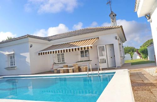 a villa with a swimming pool in front of a house at Chalet Cocle in Novo Sancti Petri
