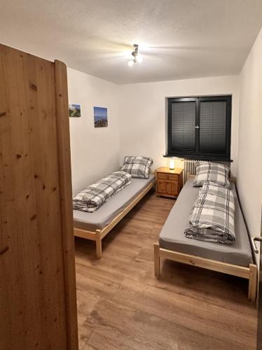 two beds are in a room with wooden floors at FeWo Schwäbeleholz mit 2 Schlafzimmern in Sonthofen