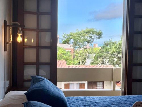 um quarto com uma cama e uma grande janela em Pousada Canajurê em Florianópolis