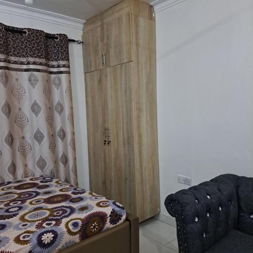 a bedroom with a wooden cabinet next to a bed at Dolphin-holiday homes mombasa in Ndome