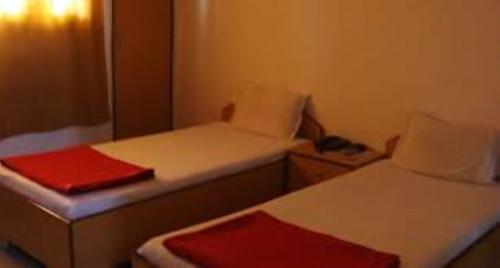 a small room with two beds and a red blanket at Residency 24X7,Bhubaneswar in Bhubaneshwar