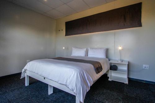 a bedroom with a large bed with white sheets and pillows at SleepOver Upington in Upington