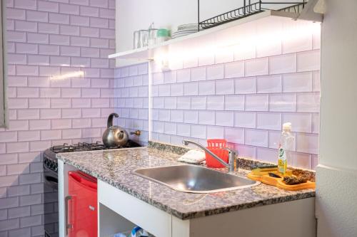 a kitchen with a sink and pink subway tiles at Descanso las Tres Marias Apart Hotel in Villa Carlos Paz