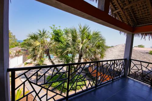 a balcony with palm trees and a view of the beach at Le jardin des délices in Mahajanga