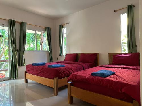 a bedroom with two beds with red sheets and windows at Sea Shell Beach Resort in Ko Lanta