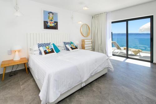 a white bedroom with a bed and a view of the ocean at Gallery Luxury Suites & Rooms-Only Adults in Split