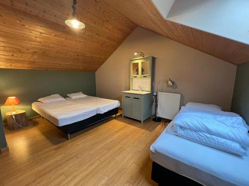 2 camas en una habitación con techos de madera en Le Bercail, en Somme-Leuze