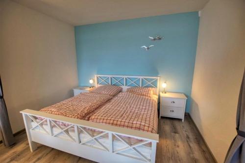 1 dormitorio con cama y pared azul en Ferienpark - Haus H, App 0H0707, en Heiligenhafen