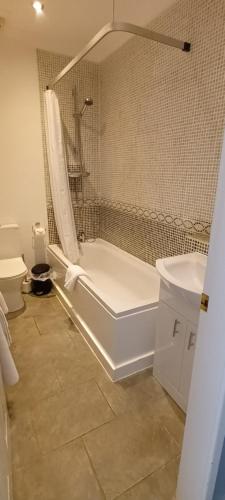 a bathroom with a tub and a toilet and a sink at Riverdale Hall Hotel & Leisure in Bellingham