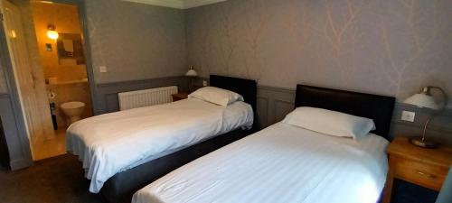 two beds in a hotel room with white sheets at Riverdale Hall Hotel & Leisure in Bellingham