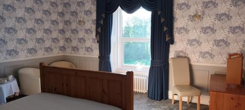 a bedroom with a bed and a window with blue curtains at Riverdale Hall Hotel & Leisure in Bellingham