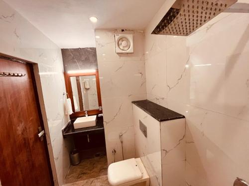 a white bathroom with a toilet and a sink at The River Grand, Mussoorie in Mussoorie